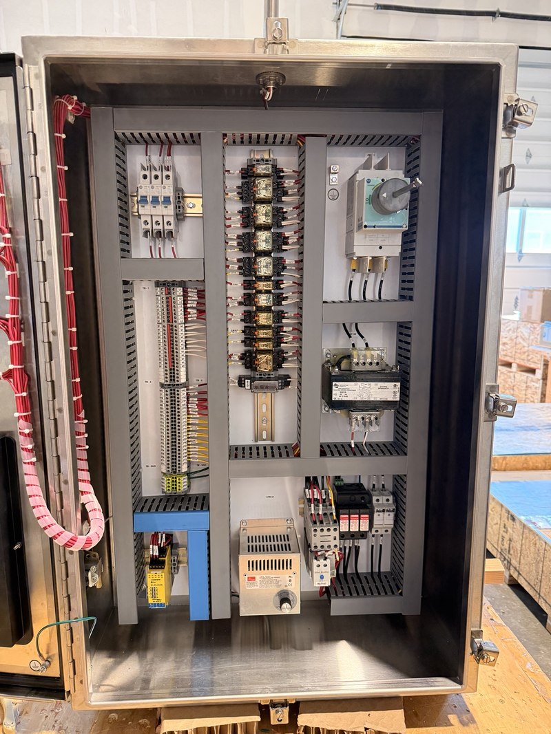 Stainless control enclosure with relay bank, disconnect, transformer, labeled terminals and motor-control components.